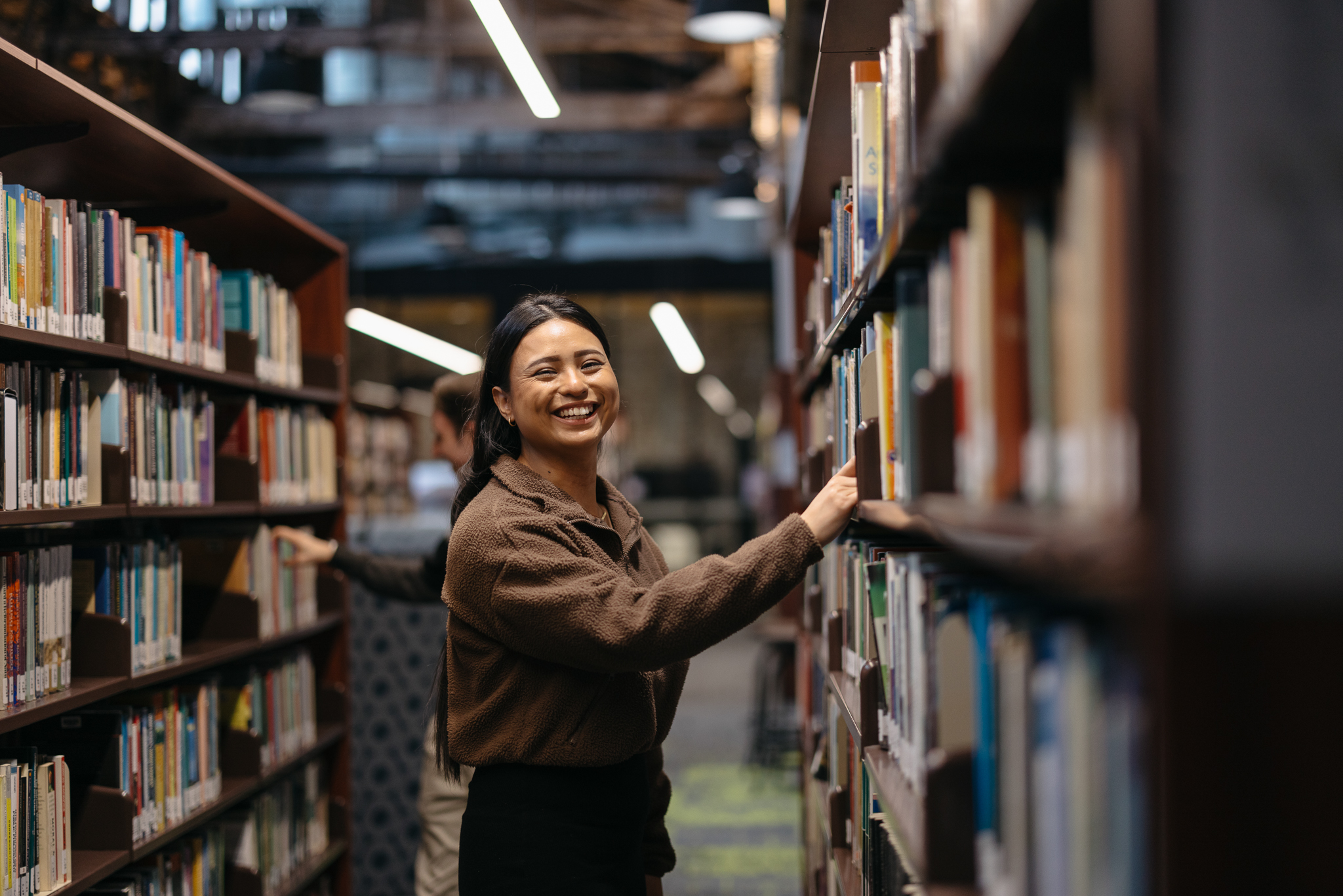 Student looking at library bookshelves