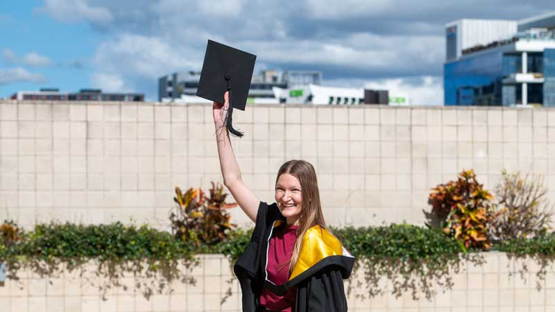 A happy Business Graduate outside of the ceremony event.