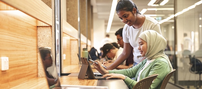 two students walking in the library 